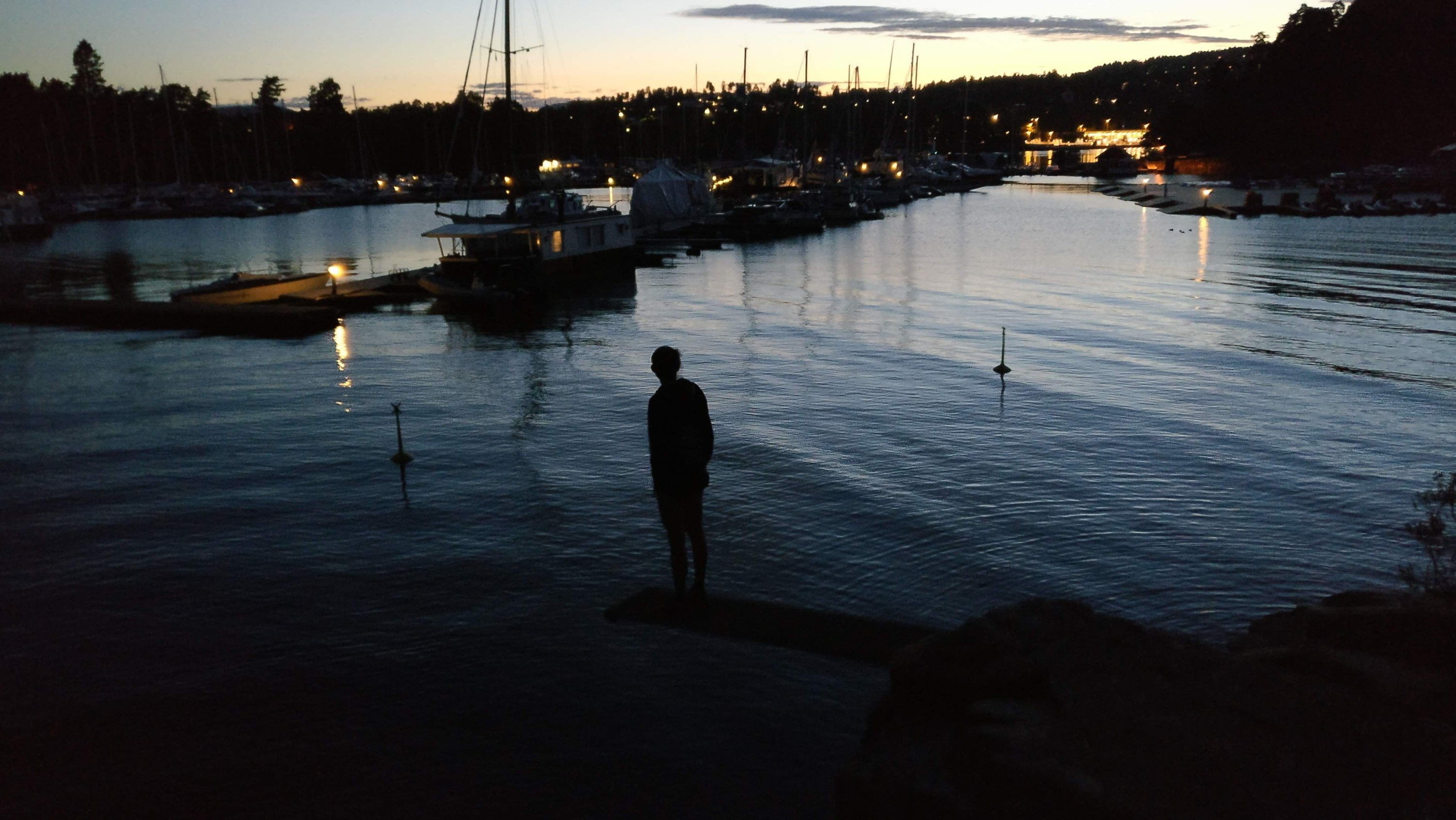 A picture of my friend by night, standing on a diving board in front of Killingen's harbor.